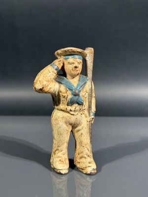 figurine représentant un marin tenant une batte de baseball, posée sur une surface réfléchissante