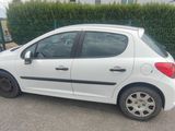 une petite voiture blanche garée sur un parking, à côté d'autres voitures