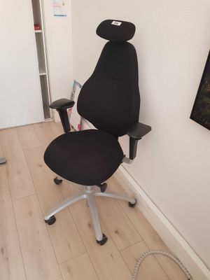 a black office chair with a black seat in the corner of a room