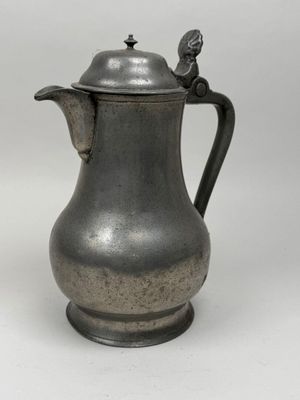 an old silver coffee pot with a bird on the top