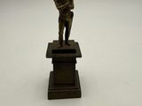 bronze figurine of a boy holding a book on a pedestal