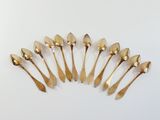 six gold spoons arranged in a circle on a white surface