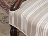 a chair with a striped upholstered seat on a rug