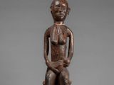 a wooden statue of a man sitting on a stool
