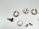 many different types of earrings and a pocket watch on the table