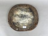 a silver plate with a design on it on a white surface