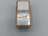 a small silver box with a picture of a boat on it