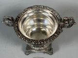 a silver bowl sitting on top of a table next to a coin