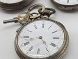 three antique pocket watches sitting on top of a white table