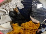 a pile of clothes that is sitting on a bed