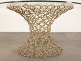 a close up of a table with a glass top and a gold metal base