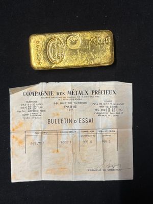 an old gold bar sitting on top of a piece of paper next to a piece of paper