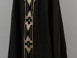 a black cape with gold and white trim on a mannequin stand