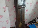 une horloge de parquet dans un coin de la pièce, à côté d'une table