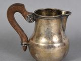 a silver pitcher with a wooden handle on a table