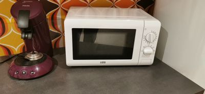 un micro-ondes blanc posé sur un plan de travail à côté d'un four à micro-ondes rose