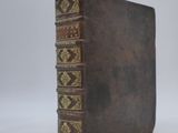 an old book with a brown cover sitting on top of a white surface