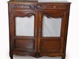 une vieille armoire en bois avec des portes vitrées et un tiroir en dessous