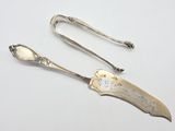 pair of antique silverware spoons and tonges on a white surface