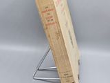 an old book sitting on top of a metal stand next to a white wall