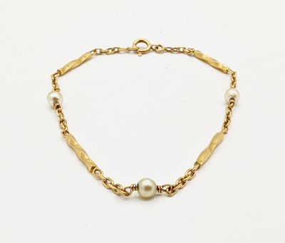 a close up of a gold bracelet with pearls on a white background