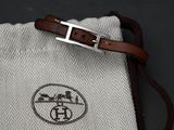 a white bag with a brown strap and a silver buckle on it