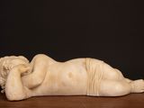 marble statue of a woman laying on her back on a wooden table