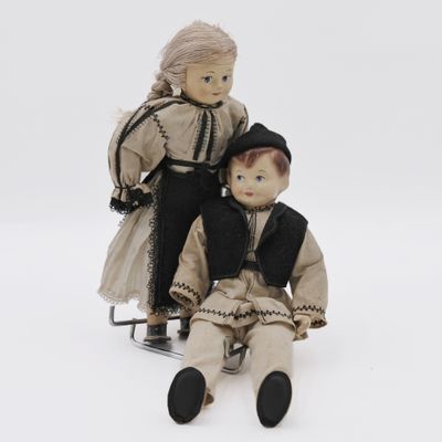 two dolls sitting next to each other on a sled