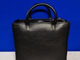 a black handbag sitting on top of a table next to a blue wall