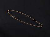 a gold plated hair pin on a black background
