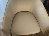 beige leather chair in front of a white curtain in a living room