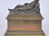 une statue antique en bronze représentant une femme allongée sur une plate-forme inclinée