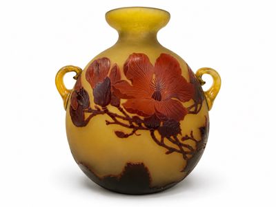 un vase jaune orné de fleurs rouges, posé sur un fond blanc