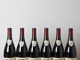 six bottles of red wine lined up on a wooden table