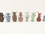 many different colored vases lined up on a white surface