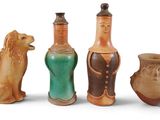 quatre vases de couleurs différentes sont alignés sur une surface blanche