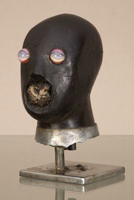 une sculpture représentant une tête d'homme posée sur un socle métallique