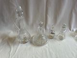 cinq bouteilles en verre et une carafe en verre posées sur une table