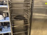une étagère en acier inoxydable avec des casseroles et des poêles dans une cuisine