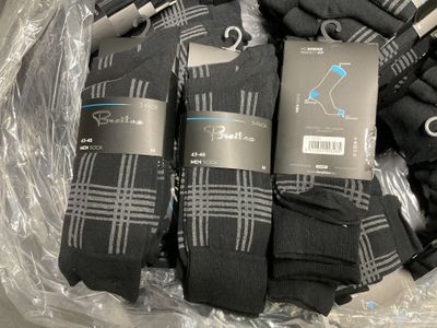 several pairs of men ' s black socks in a plastic bag