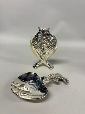 two silver spoons with a bird on them sitting next to each other