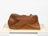 sculpture of a reclining figure on a pedestal on a white surface