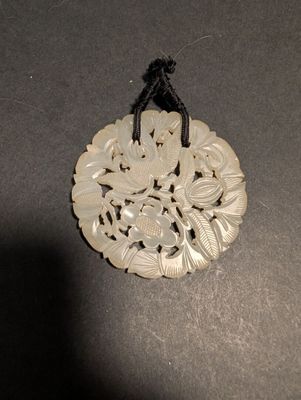 un pendentif blanc orné d'un motif, posé sur une table