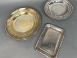 three silver plates and a silver tray on a table