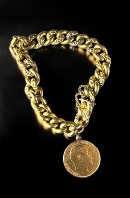 a close up of a gold chain bracelet with a coin on it