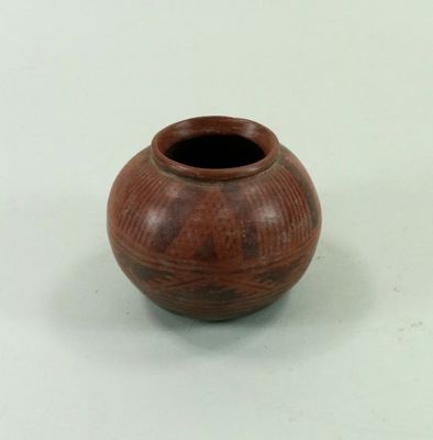 un petit vase brun posé sur une surface blanche