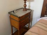 a small table with a lamp on top of it next to a bed