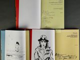 three open books on a table with a drawing of a woman in a hat and a drawing of a man in a hat