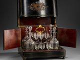 bottles and glasses in a wooden case with a clock on top