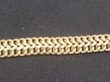 gros plan d'un bracelet en or sur une surface noire